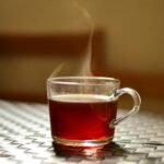 A steaming glass of tea adds warmth to an indoor setting, captured in a modern style.